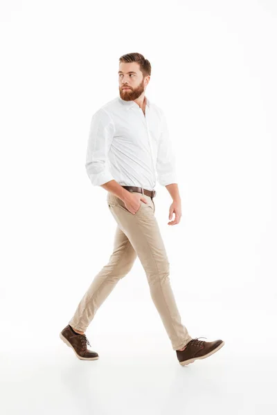 Handsome young bearded man walking over white wall — Stock Photo, Image