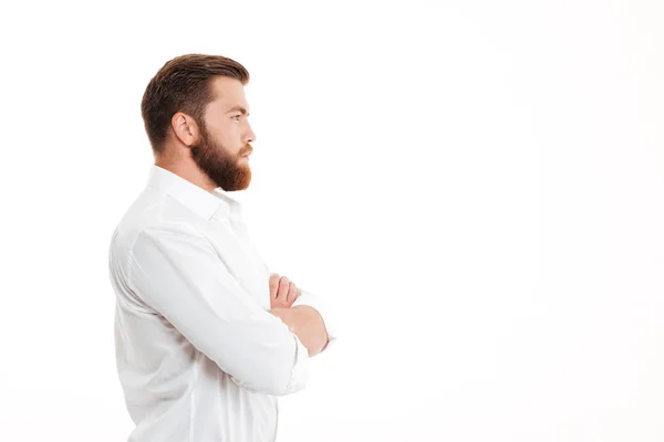 Alvorlig, ung skjeggete mann som står over hvit vegg – stockfoto