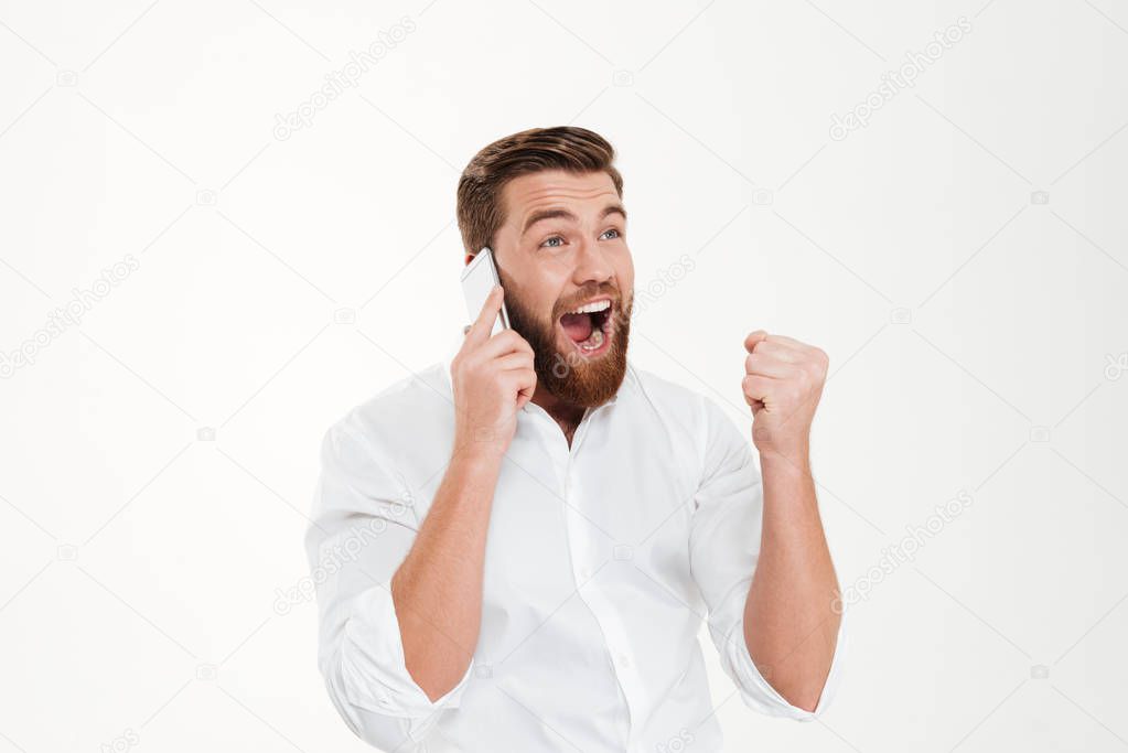 Happy young bearded emotional man talking by phone.
