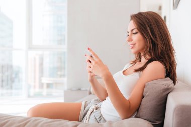 Cep telefonu kullaranarak gülümseyen çekici kadın