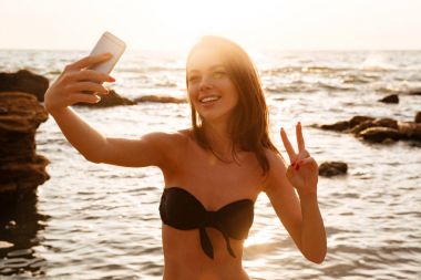 Selfie onun Smartphone'da yapma bikini neşeli esmer kadın