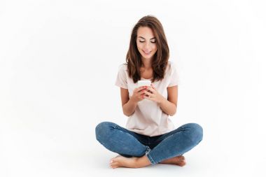 Katta oturan ve smartphone kullanarak gülümseyen esmer kadın