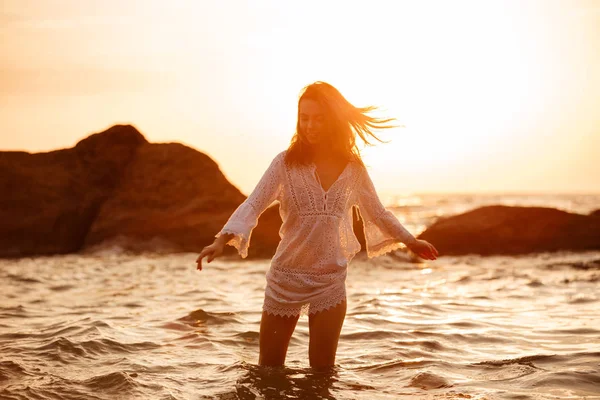 Задоволена брюнетка жінка в світлому літньому платті рухається в морі — стокове фото