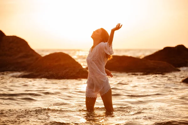 Mujer morena segura en vestido de verano ligero jugando en el mar —  Fotos de Stock