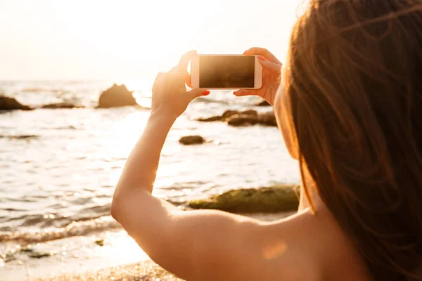 Visão traseira da mulher morena fazendo foto em seu smartphone — Fotografia de Stock