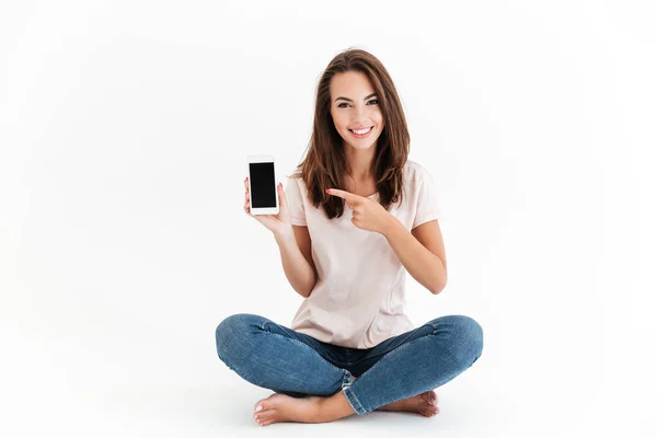 Mujer morena sonriente mostrando pantalla de teléfono inteligente en blanco — Foto de Stock