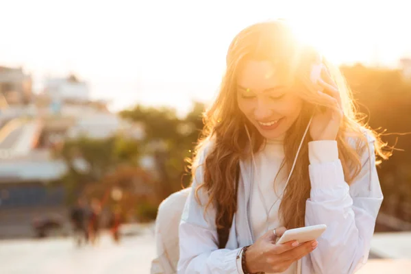 微笑的黑发女人，在秋天的衣服使用她的智能手机 — 图库照片