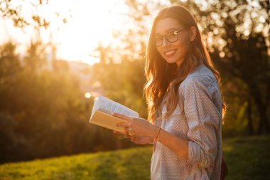 Kitap gözlük gülümseyen esmer kadın yan görünüm