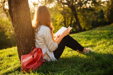 Ağacın yanında oturan güzellik esmer kadın yan görünüm