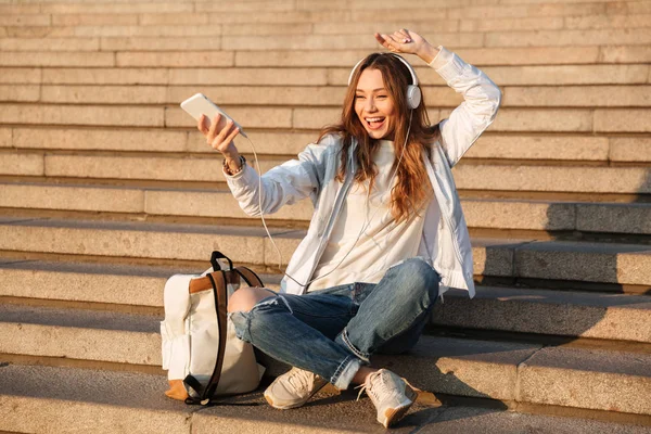 Lachen gelukkig brunette vrouw zitten op trappen met rugzak — Stockfoto