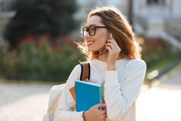 Mujer morena agradable en gafas y ropa de otoño escuchando música —  Fotos de Stock