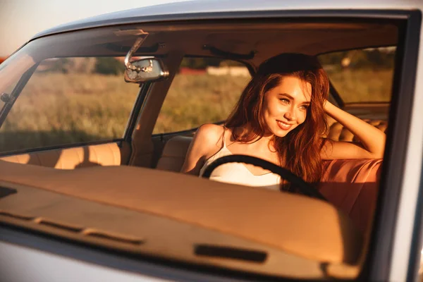 Uśmiechnięta brunetka kobieta siedzi wewnątrz samochodu — Zdjęcie stockowe