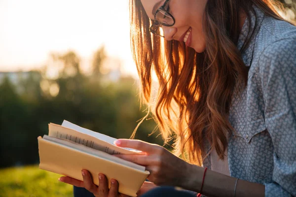 Abgeschnittenes Bild einer lächelnden brünetten Frau mit Brille, die Buch liest — Stockfoto