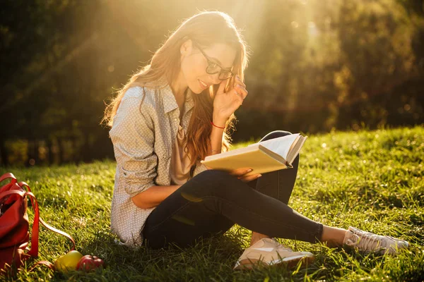 Brünette Frau mit Brille sitzt auf Gras — Stockfoto