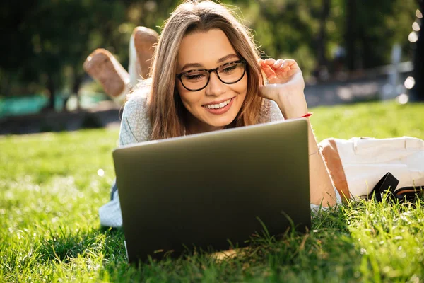 Happy bruneta žena v brýlích, ležící na trávě — Stock fotografie
