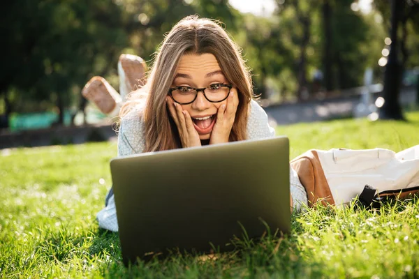 Sorprendido morena mujer en gafas que yacen en la hierba — Foto de Stock