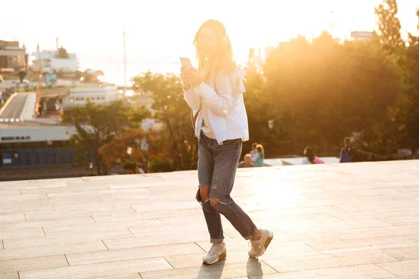 Heureuse femme brune en vêtements d'automne en utilisant smartphone et danse — Photo