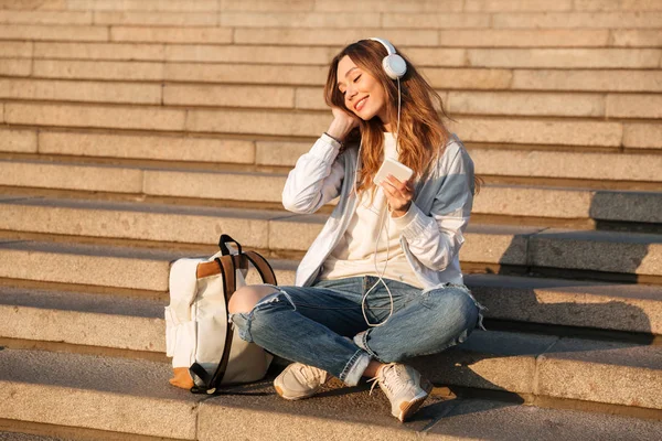 Femme brune insouciante en vêtements d'automne assis sur les escaliers — Photo