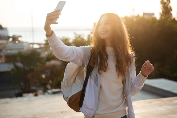 Sorridente donna bruna in abiti autunnali facendo selfie su smartphone — Foto Stock