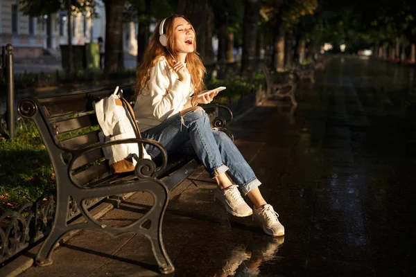 Laughing brunette woman in autumn clothes sitting on bench — Stock Photo, Image