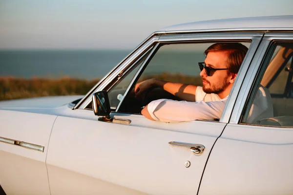 Vista lateral del hombre seguro en gafas de sol sentado en el coche — Foto de Stock