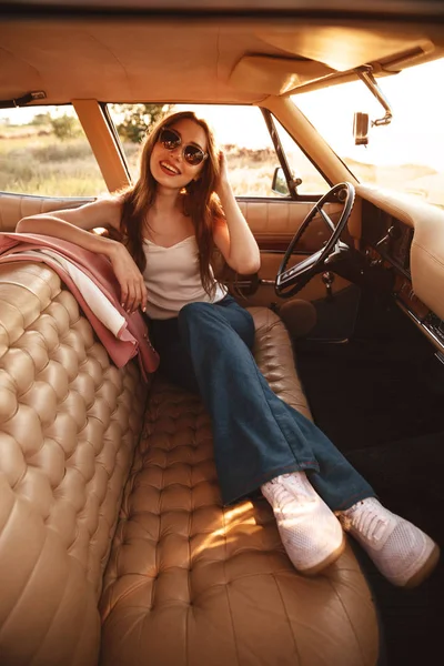 Pionową obrazu atrakcyjna kobieta w okulary siedzi wewnątrz samochodu — Zdjęcie stockowe