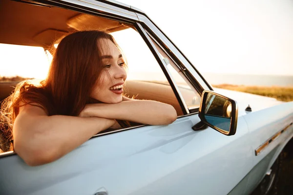 Close-up zijaanzicht van lachende vrouw in zonnebril zit in — Stockfoto