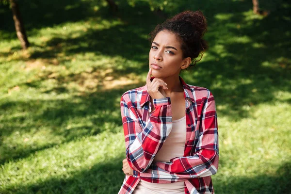 Açık havada parkta oturan genç Afrikalı kadın düşünme.