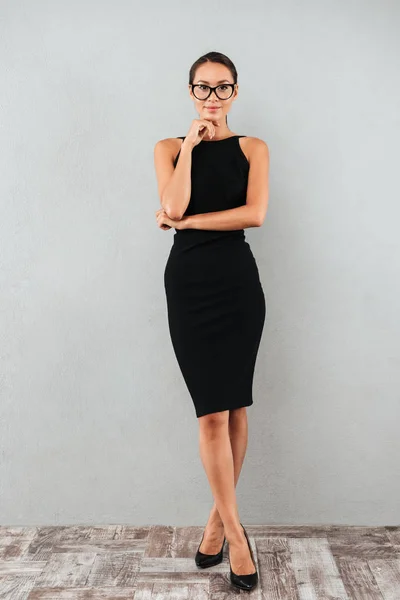 Lachende jonge zakenvrouw in zwarte jurk en brillen — Stockfoto