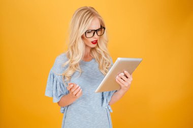 Tablet bilgisayar kullanan ciddi genç sarışın kadın.