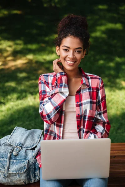 Sonriente joven africana sentada al aire libre en el parque —  Fotos de Stock