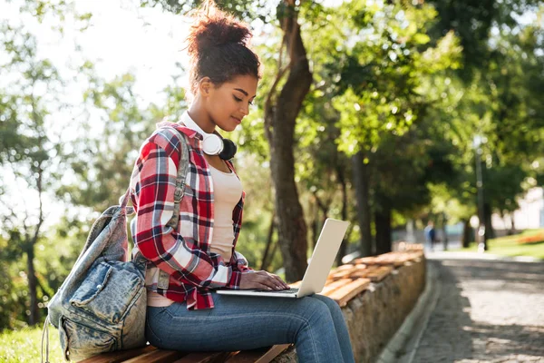 在户外坐在公园使用膝上型计算机的非洲女人. — 图库照片