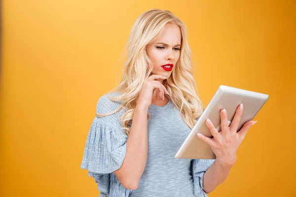 Mujer rubia joven confundida usando tableta . — Foto de Stock