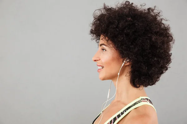 Porträtt i profil av lockigt fitness kvinna lyssnar musik — Stockfoto