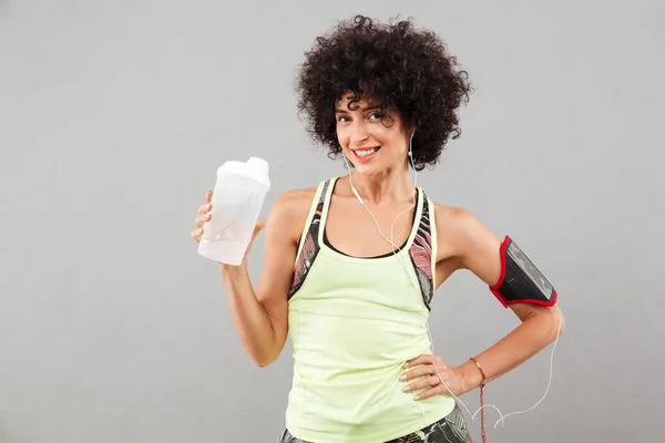 Glücklich lockige Fitness-Frau mit Wasser in der Hand — Stockfoto