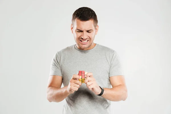 Homme confus essayer de résoudre Rubik's cube . — Photo
