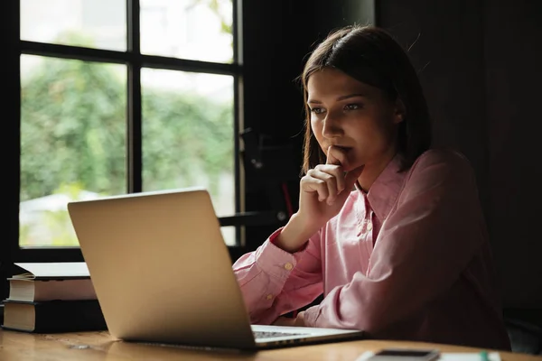 Vista lateral de la mujer concentrada sentada por la mesa en la cafetería — Foto de Stock