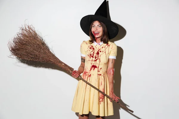 Mulher agradável em traje de Halloween como bruxa segurando vassoura — Fotografia de Stock