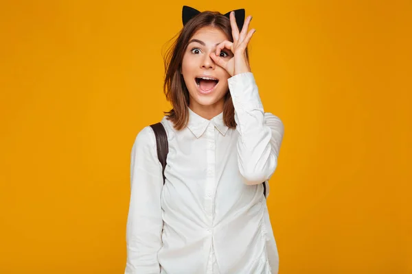 Portrait of a funny schoolgirl with backpack showing ok gesture — Stock Photo, Image