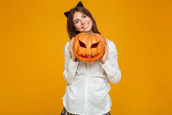 Szczęśliwy nastolatek uczennica w mundurze gospodarstwa halloween dynia — Zdjęcie stockowe