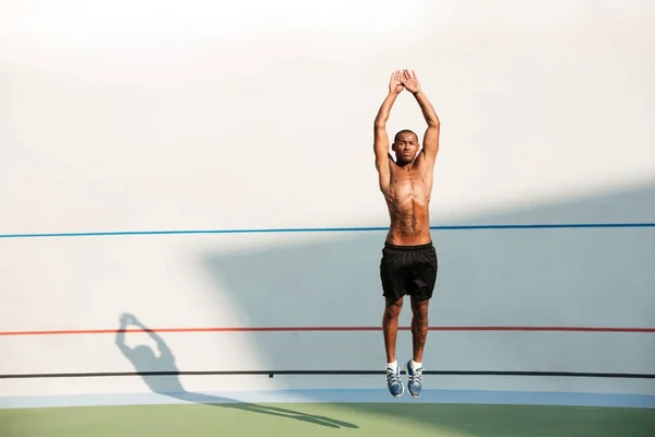 Retrato de comprimento total de um homem de fitness africano seminua pulando — Fotografia de Stock