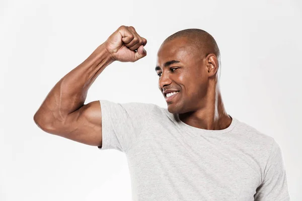 Jovem homem africano alegre mostrando bíceps . — Fotografia de Stock