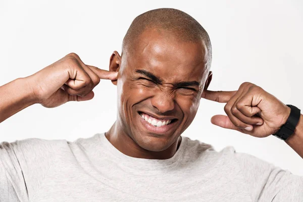 Missnöjd afrikanska man stänger öronen från ett ljud. — Stockfoto