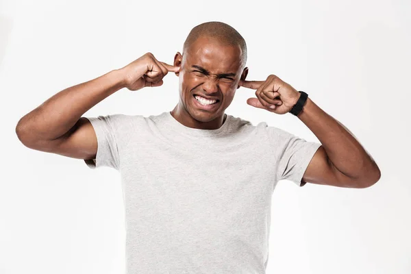 Displeased african man closes ears from a noise. — Stock Photo, Image