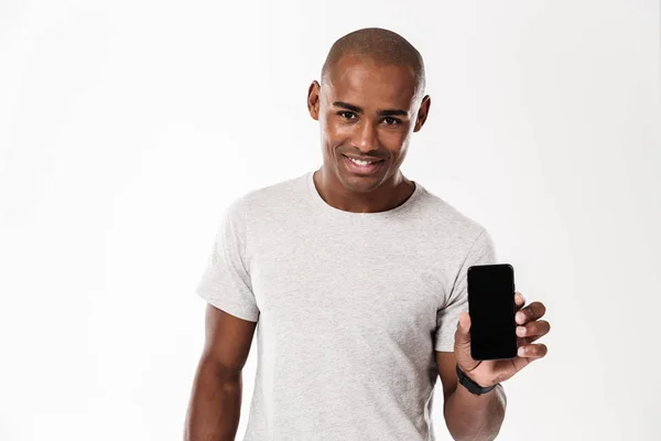 Vrolijke jonge Afrikaanse man tonen weergave van mobiele telefoon. — Stockfoto