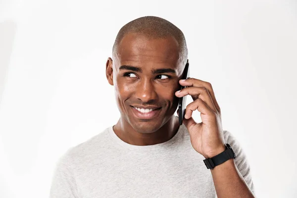 Sonriente hombre africano hablando por teléfono inteligente y mirando hacia otro lado — Foto de Stock