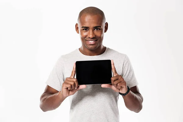Heureux homme africain montrant écran de tablette vierge — Photo