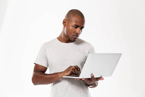 Bonito jovem homem africano usando computador portátil — Fotografia de Stock