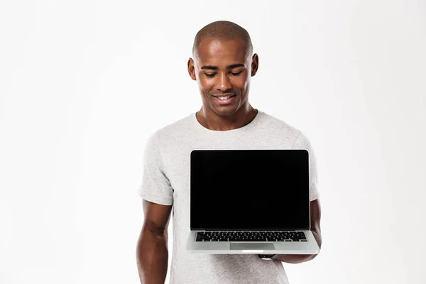 Heureux jeune homme africain montrant l'affichage de l'ordinateur portable — Photo