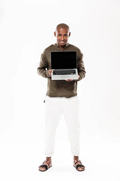 Imagen completa del hombre africano feliz mostrando una computadora portátil en blanco —  Fotos de Stock